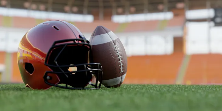 A football helmet and ball resting on the grass field.