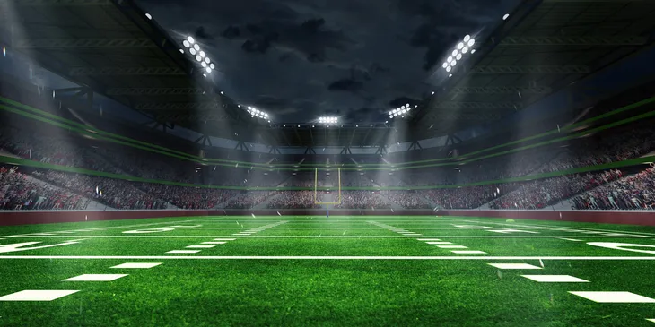 Illuminated football field under stormy night sky.