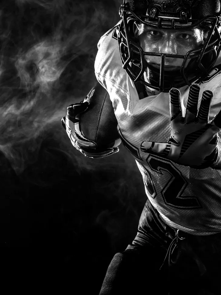 Dramatic black-and-white image of an American football player in action.