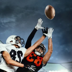 Two football players reaching for the ball mid-air during a game.