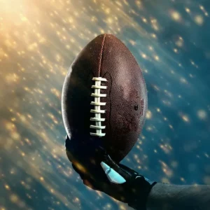 Hand holding a football against a glowing background.