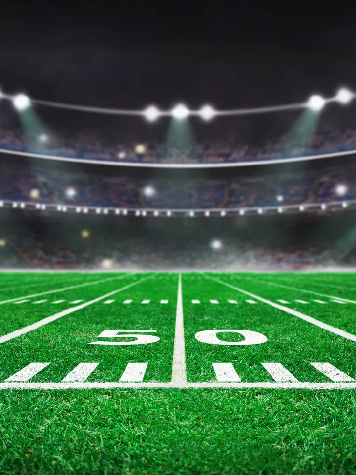 Empty football field under bright stadium lights at night.