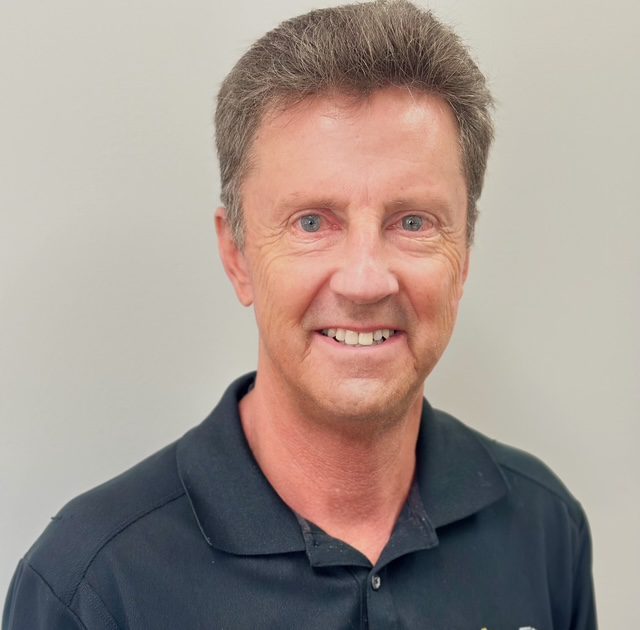 Smiling man in a black polo shirt.